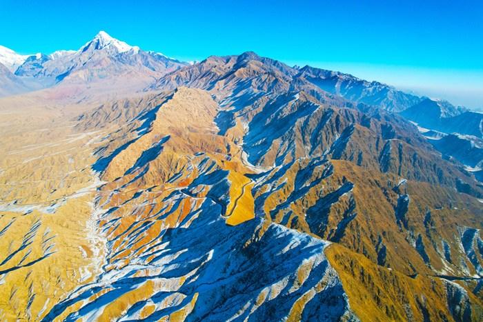 新疆阿克蘇山區(qū)雪后壯美巍峨 陽光下群山黃白相間